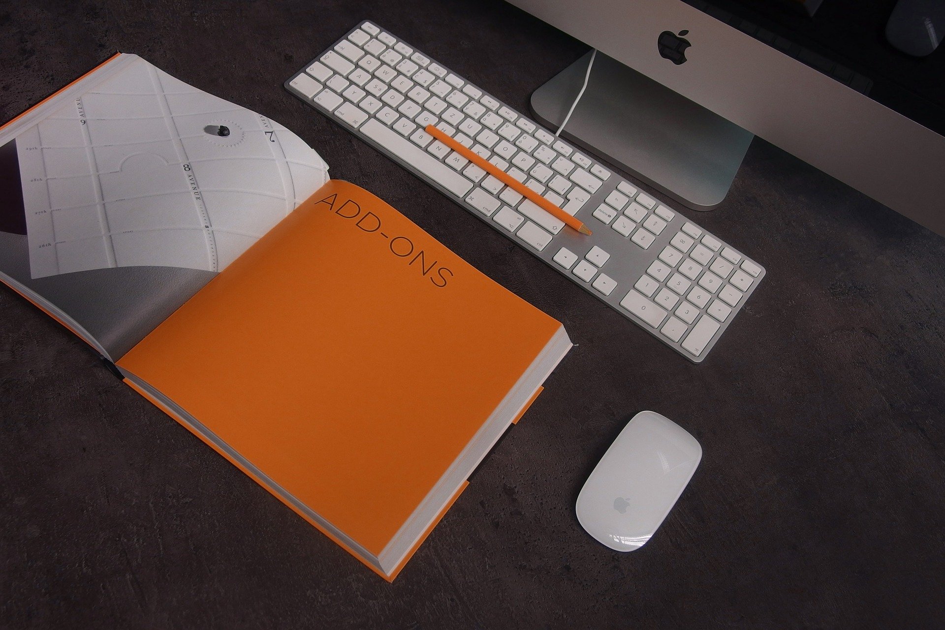 Una libreta naranja y un ordenador para investigar sobre el seguro de responsabilidad civil