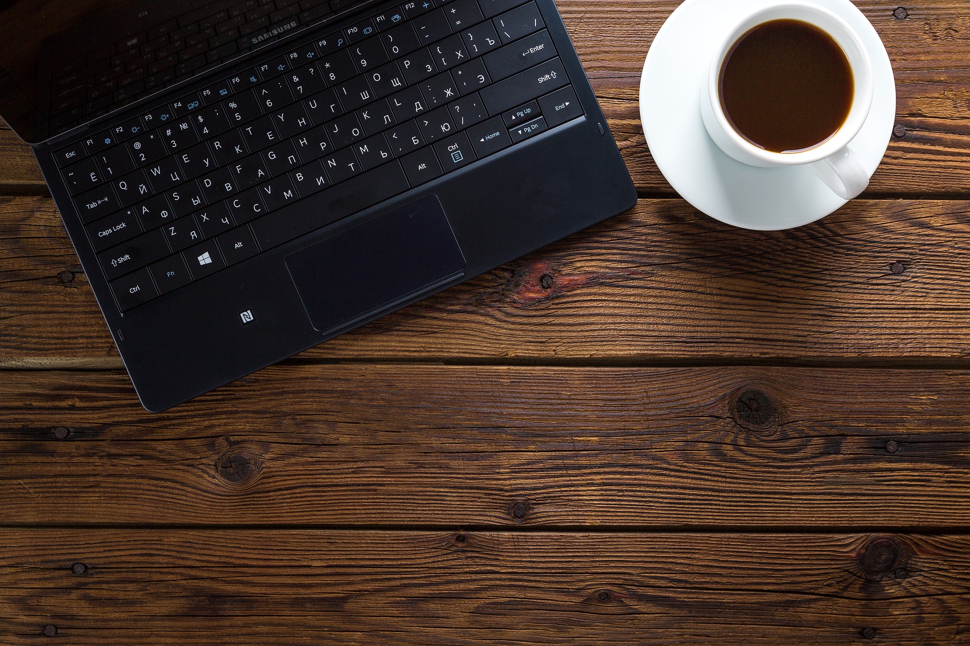 Un ordenador y una taza de café para elegir la mejor gestoría online