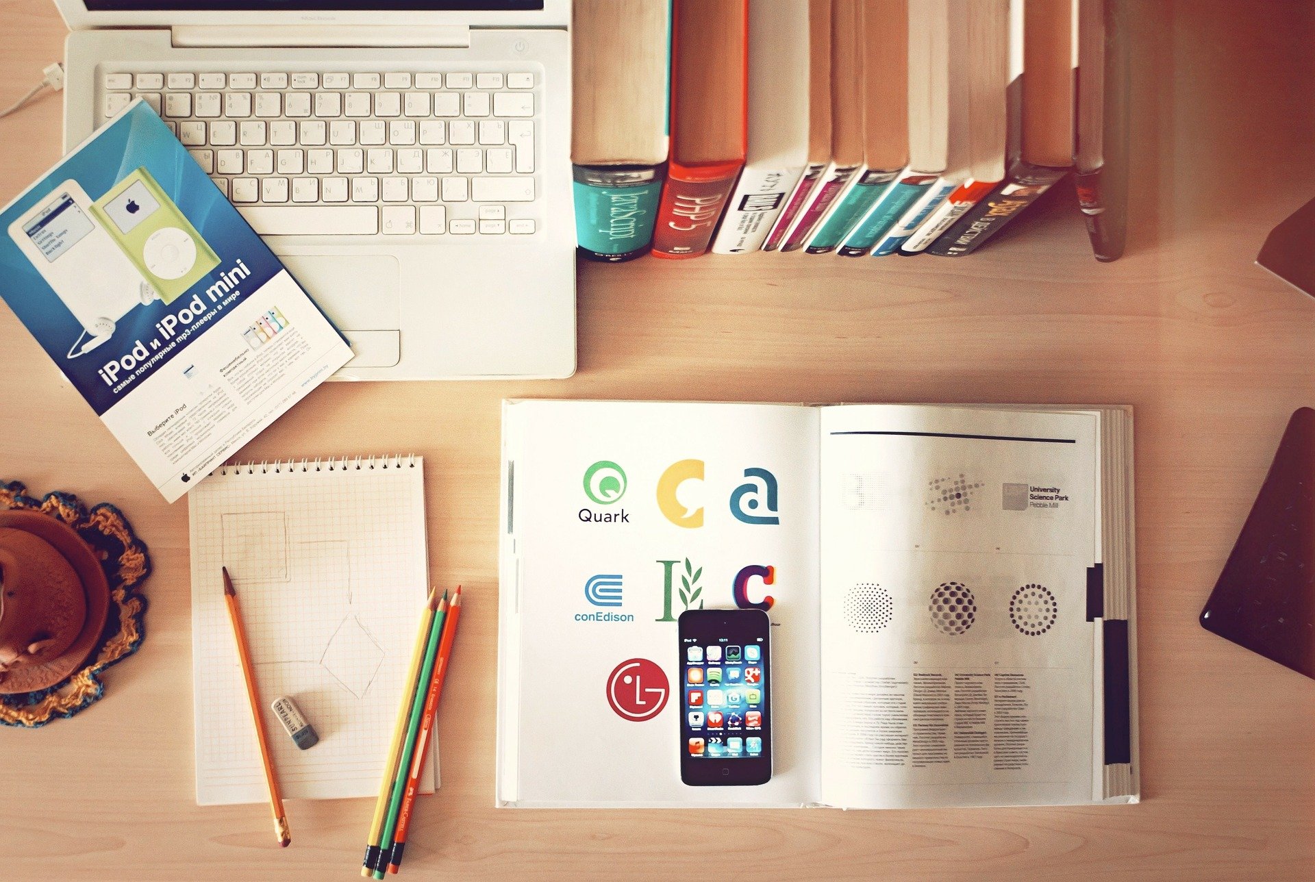 Una mesa con un móvil, libros, un ordenador y bolis para buscar información sobre el modelo 145