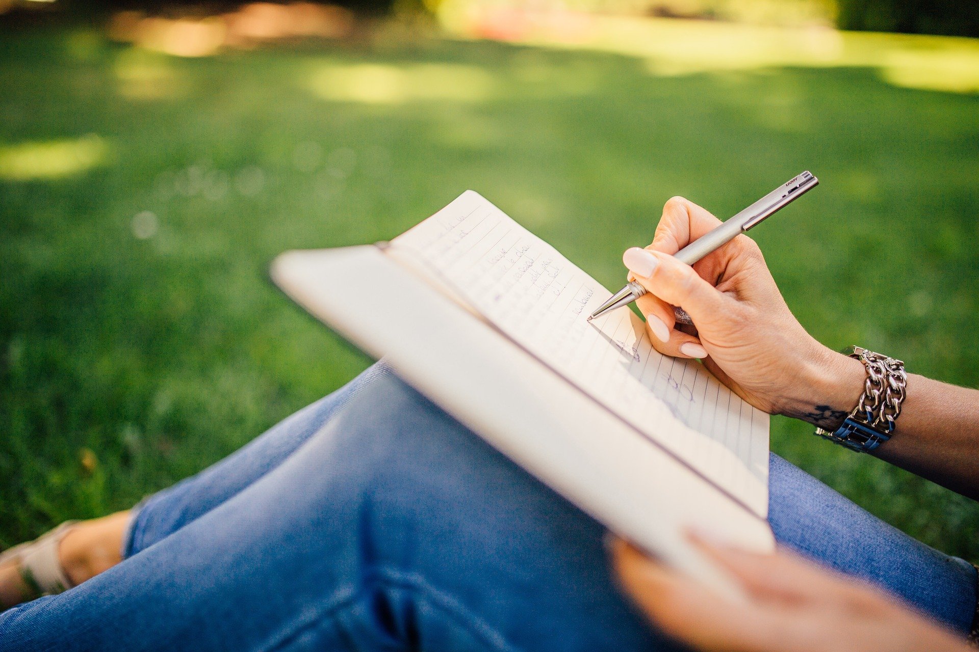 Las manos de una chica escribiendo en una libreta en el campo sobre el seguro de incapacidad para autónomos y otros beneficios fiscales