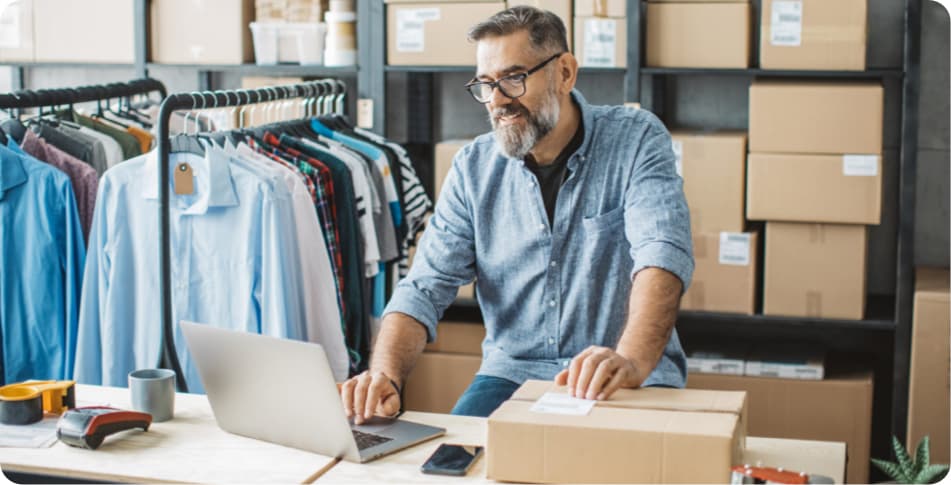 Un autónomo con un ordenador en un almacén viendo las ventas de su ecommerce