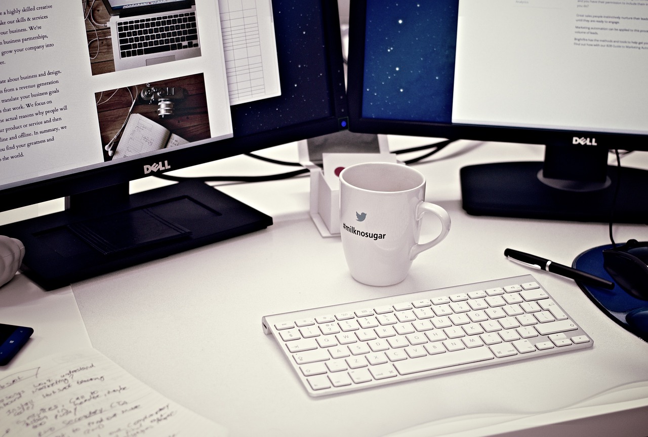 Dos ordenadores, una taza y un teclado de un autónomo para revisar la factura electrónica y el kit digital.